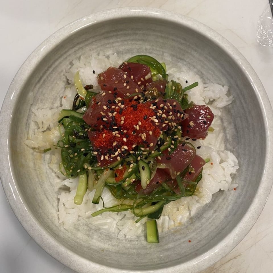 Poke Box Sushi Bar's poke bowl with tuna, seaweed salad, cucumber, tobiko, and sesame seeds over rice.