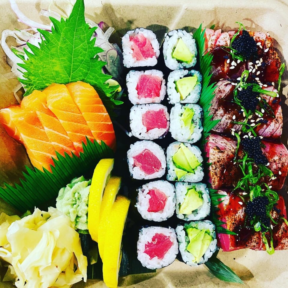 A sushi platter with salmon sashimi, tuna and avocado rolls, and seared tuna with caviar.