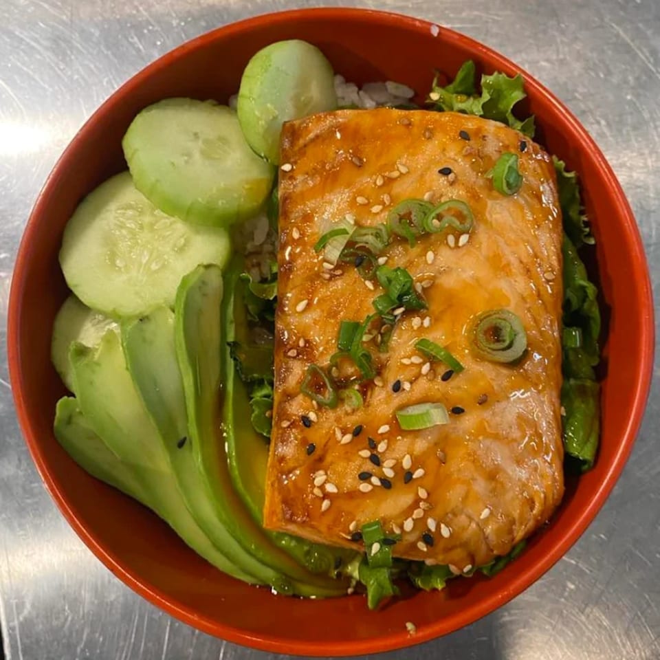 A Poke Box Sushi Bar salmon poke bowl with avocado, cucumbers, and green onions.